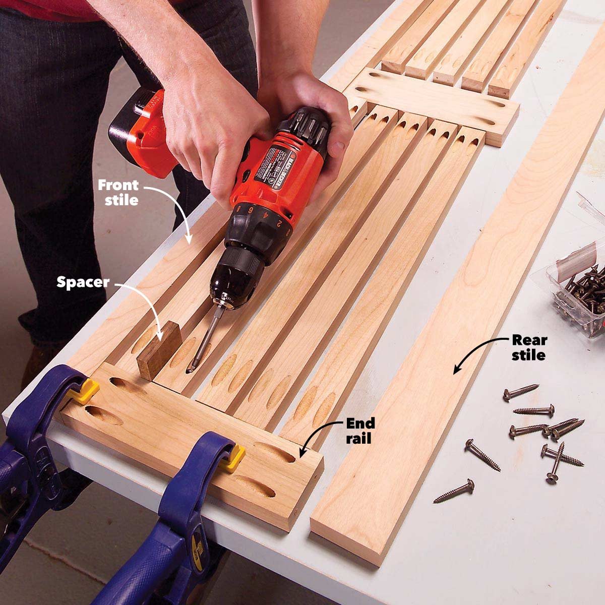 A person drills into wooden pieces on a worktable, assembling components labeled as front stile, rear stile, spacer, and end rail, surrounded by screws and clamps.
