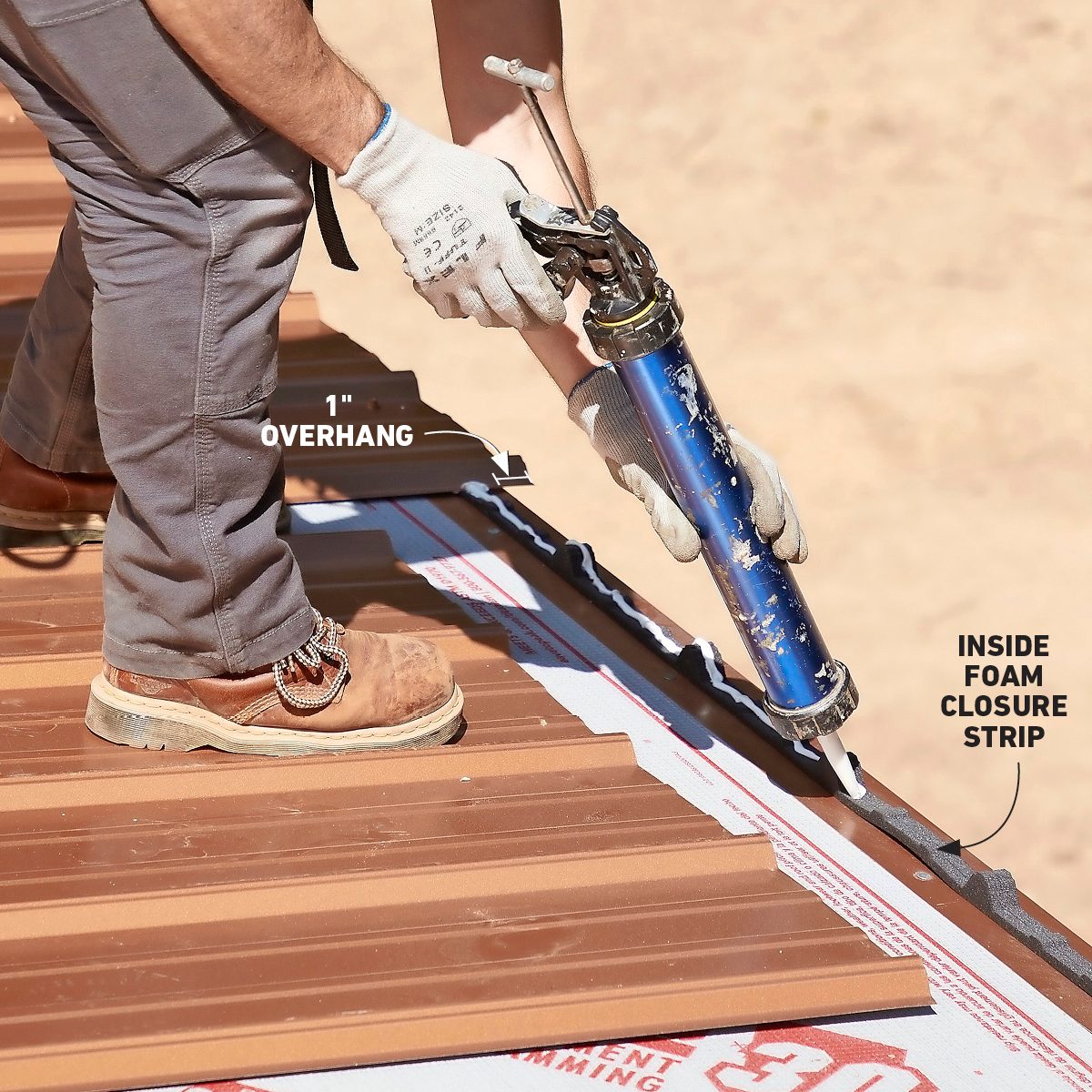 A worker applies sealant using a caulking gun on a metal roof, standing on slanted panels, with foam closure strips visible beneath.